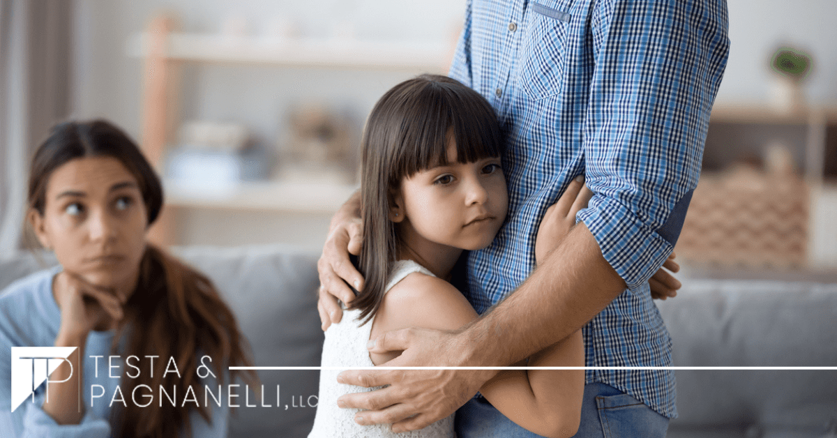 sad child hugging dad while mom watches