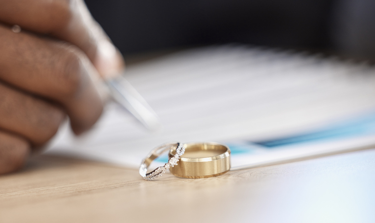 wedding rings in the foreground of a person signing document