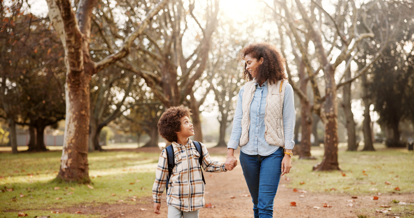 mother and son holding hands while walking through a park