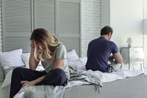 couple sitting on opposite ends of a bed